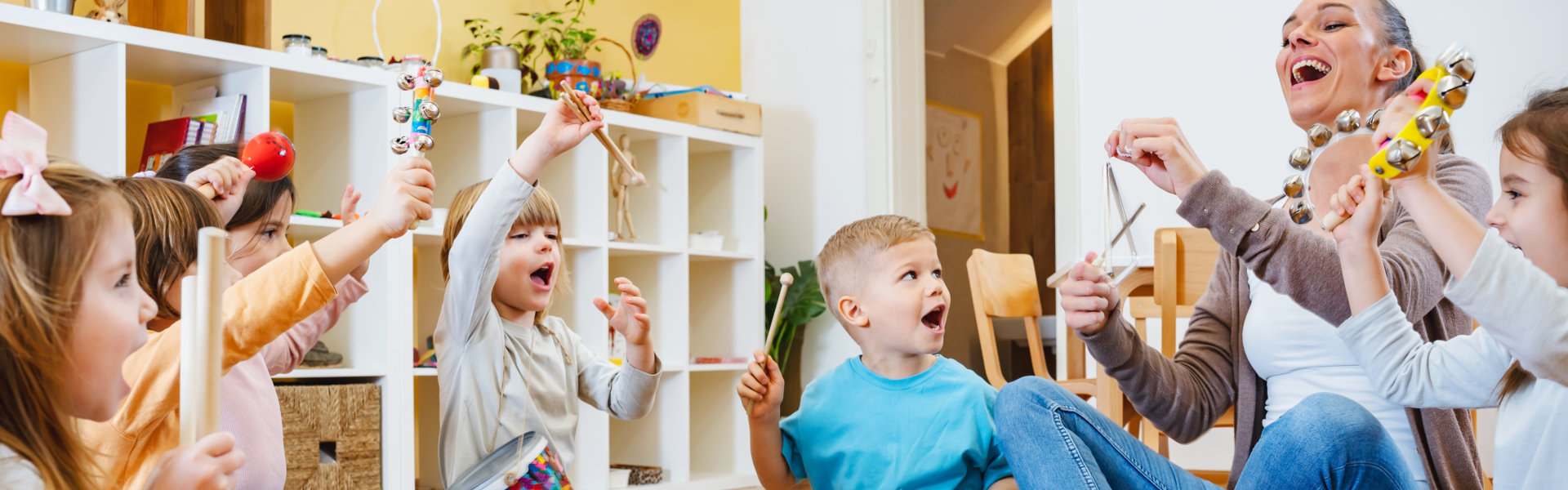 Kindergarten teacher with children sitting on the floor having music class